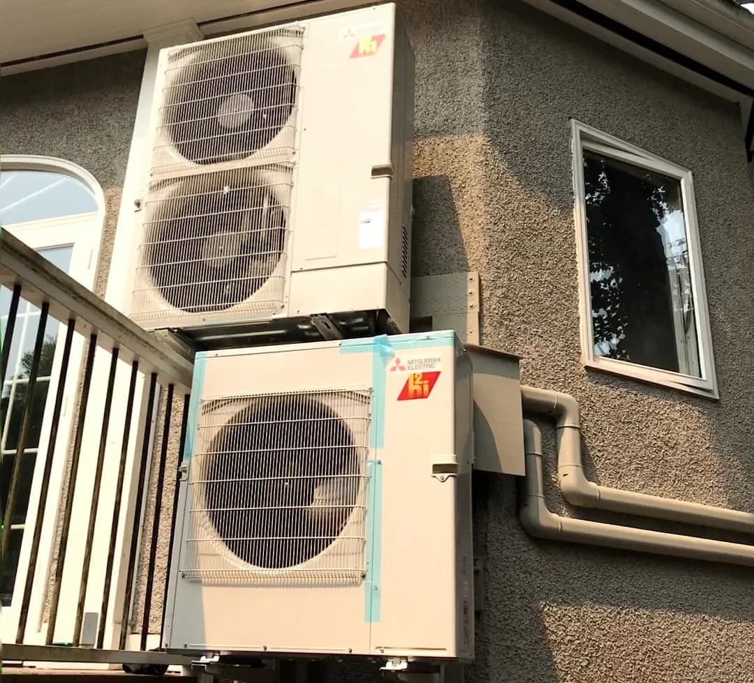 Two stacked Mitsubishi Electric outdoor AC units mounted on exterior stucco wall of Toronto home