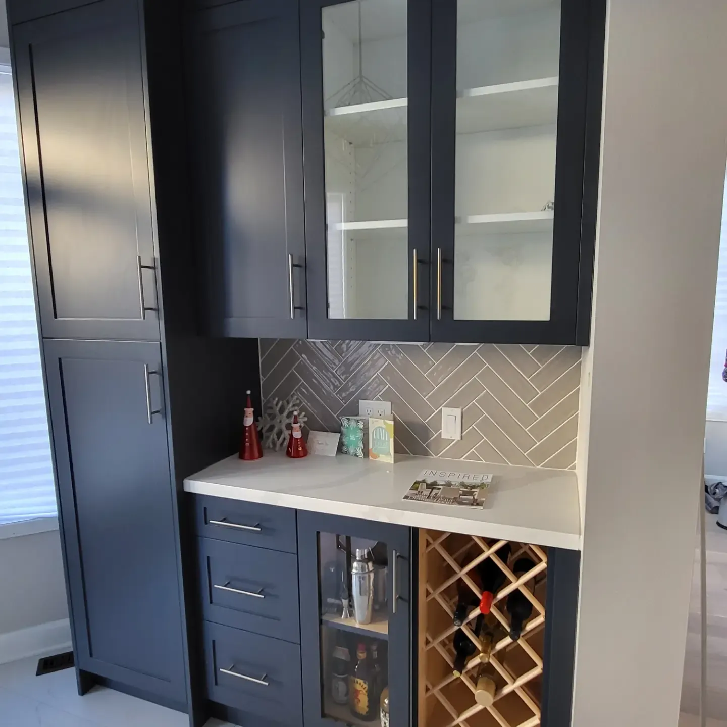 Navy blue shaker cabinets with glass doors, white quartz countertop, herringbone tile backsplash, and built-in wood wine rack in Oakville kitchen
