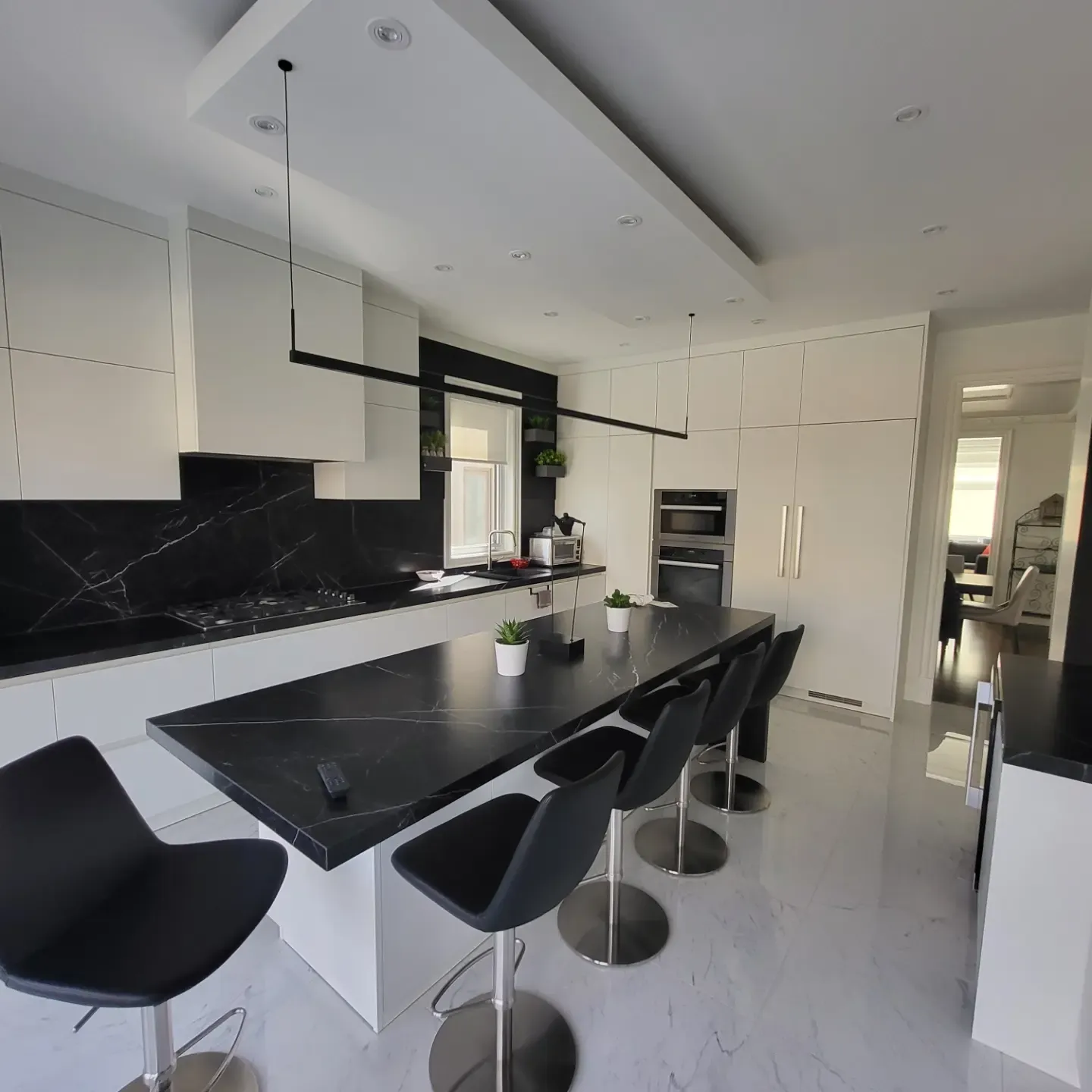 Modern black and white Toronto kitchen with large marble-look island, bar stools, and floor-to-ceiling white cabinetry